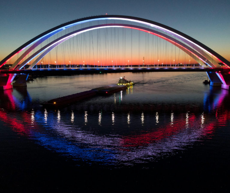 Centennial Bridge in Quad Cities Iowa and Illinois illuminated with red white and blue lights reflecting in the Mississippi River at night
