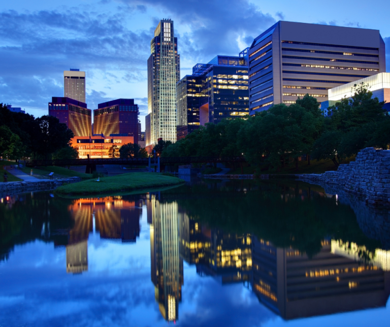 Lincoln Nebraska city skyline with tall buildings reflected in a pond or river at twilight blue hour
