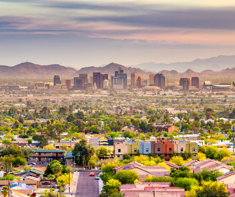 Aerial view of Phoenix Arizona city skyline surrounded by desert landscape and mountains at sunset